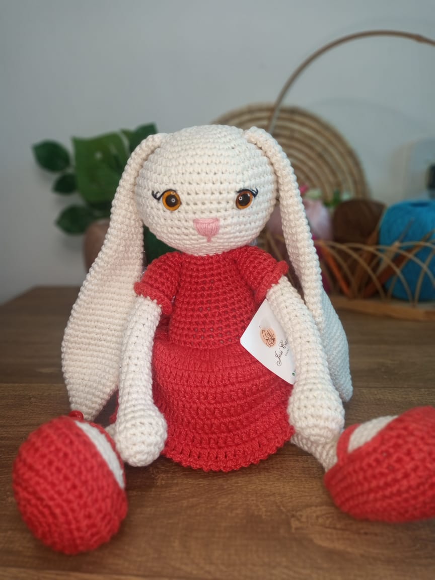 Coelha artesanal sentada com vestido vermelho